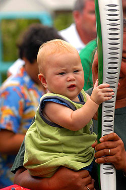 Aitutaki. As the relay continues throughout the Cook Islands, the baton is welcomed to the southern island of Aitutaki, where this baby is mesmerized by its glowing lights and unique shape.